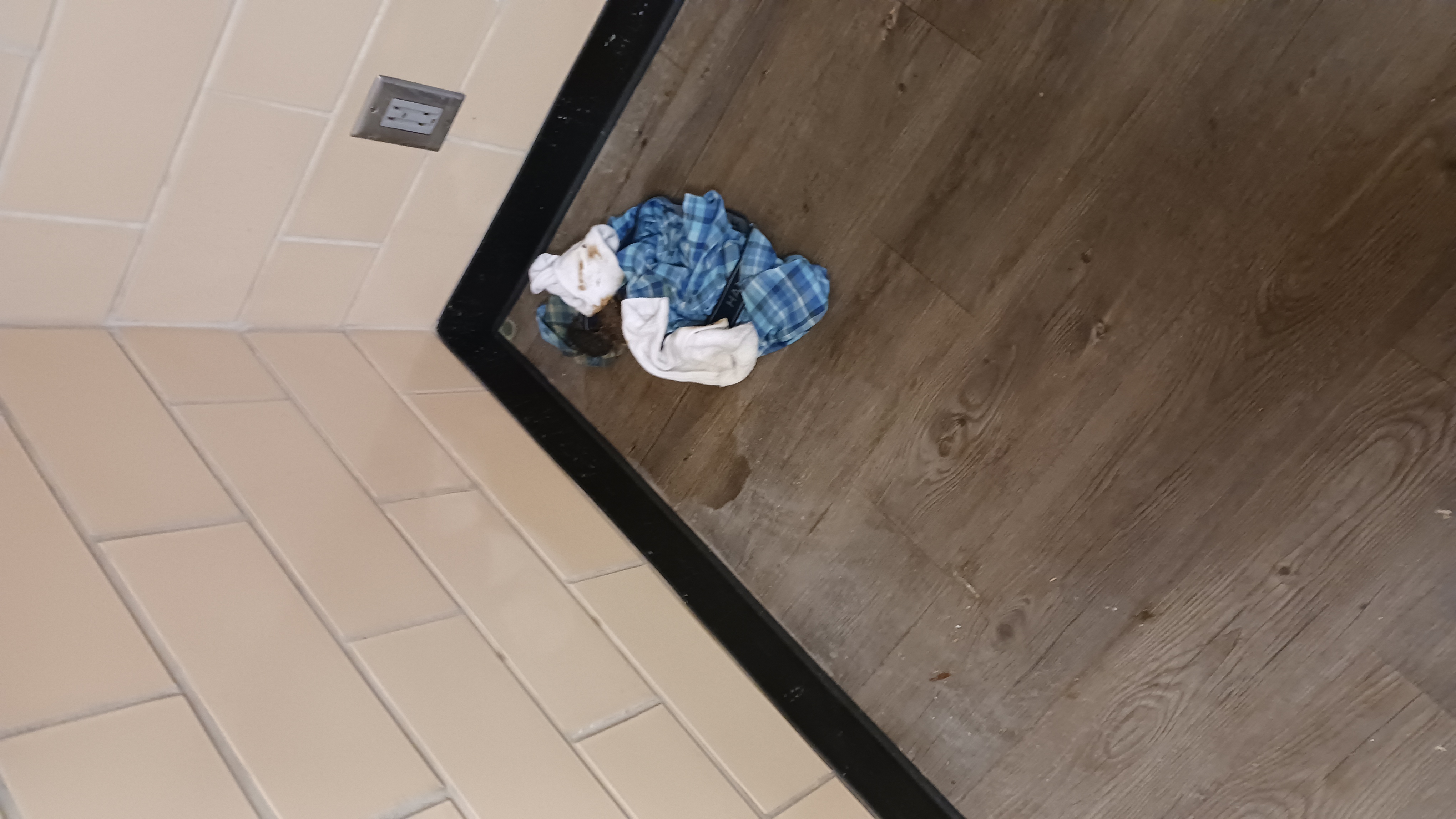 Basement common area, soiled clothing and wet floor at the base of a tiled wall